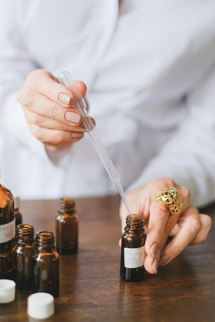 pexels photo 5682715 5682715 Close-up of hands using a dropper with brown glass bottles for essential oils.